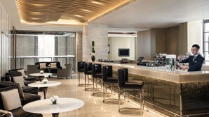 A modern bar area with a bartender, leather seating, and a polished floor.