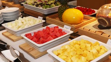 Un bufé con diversas frutas y ensaladas.