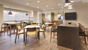 A spacious dining area with multiple tables and chairs, a central serving counter, and pendant lighting. - Fairfield Inn & Suites by Marriott Boulder Longmont (Longmont)
