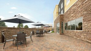 An outdoor patio area with brick flooring, outdoor furniture, and umbrellas. - Fairfield Inn & Suites by Marriott Boulder Longmont (Longmont)
