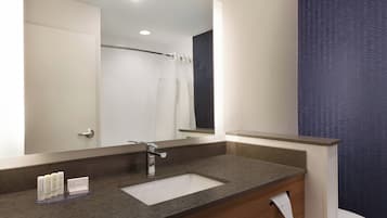 Un baño moderno con un espejo grande, un lavamanos y una cortina de ducha.