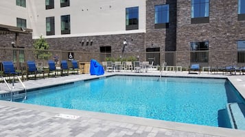 Een buitenzwembad, ligstoelen bij het zwembad