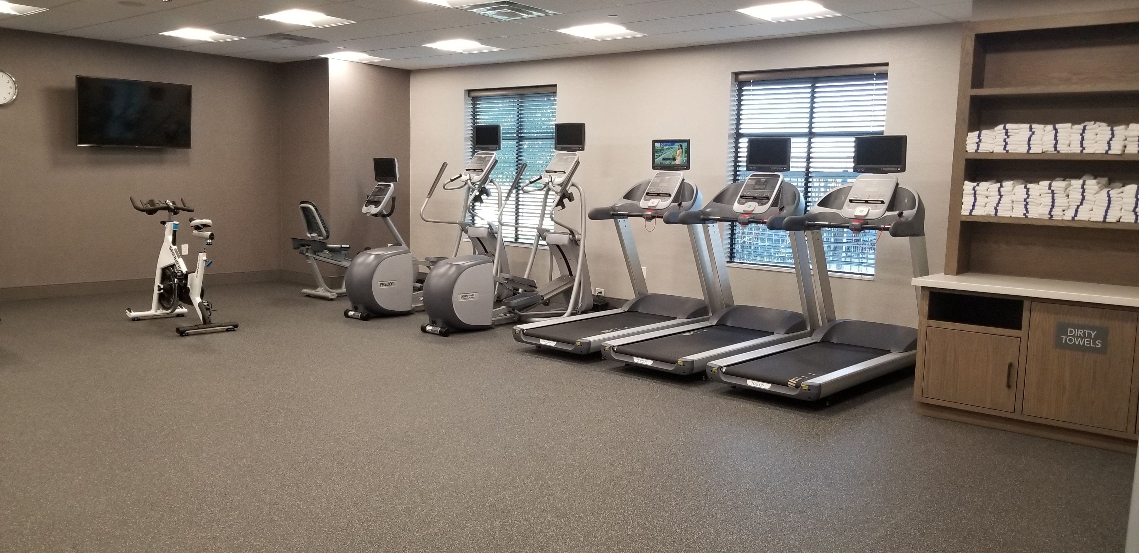 Un gimnasio con cintas de correr, elípticas y una bicicleta estática.