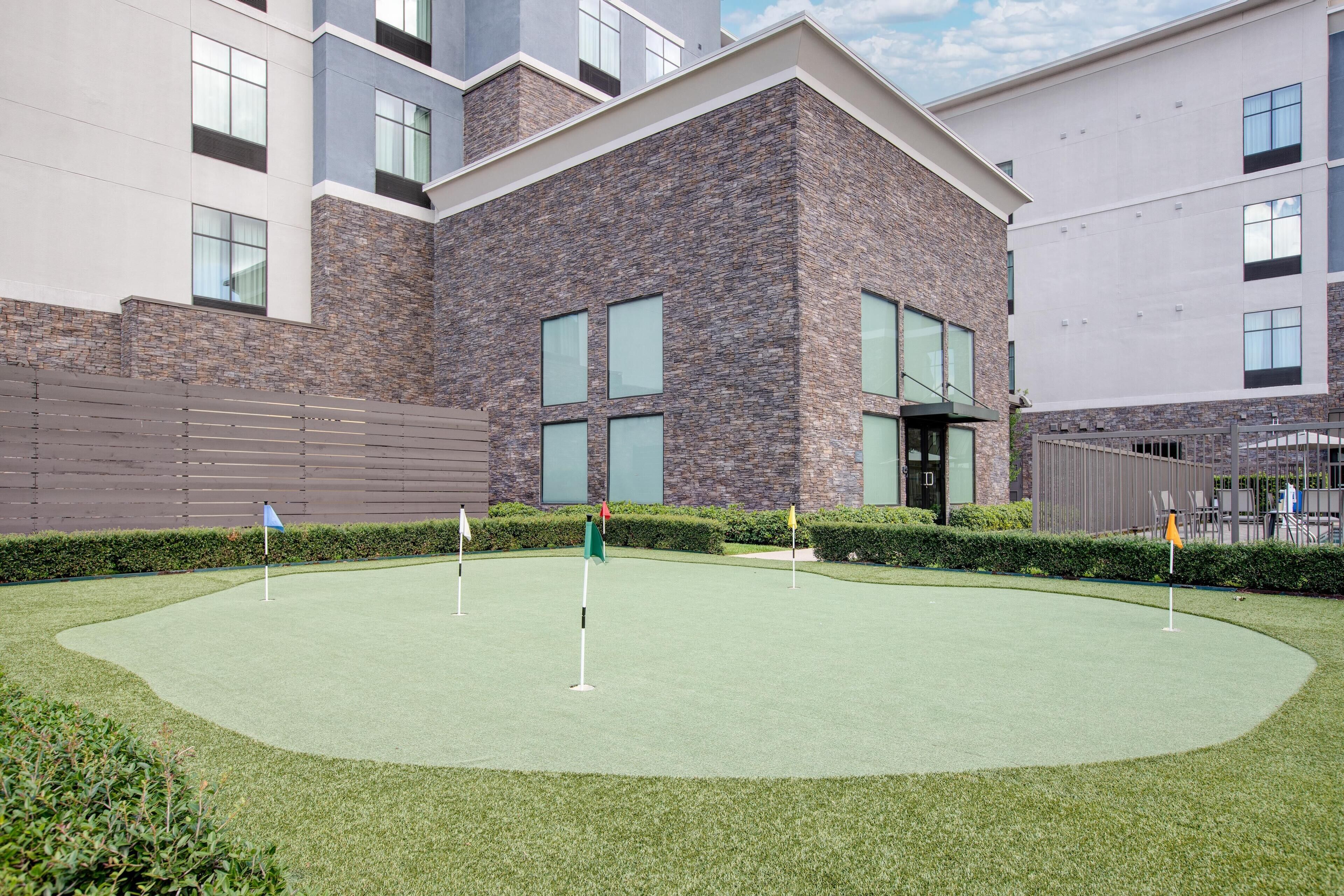 Ein Gebäude mit Innenhof, der einen Kunstrasen-Golfplatz beherbergt.