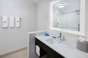 A modern bathroom with a white sink, a large mirror, and three white towels hanging on a rack. - Holiday Inn Express & Suites Sugar Land SE - Missouri City by IHG (Missouri City)
