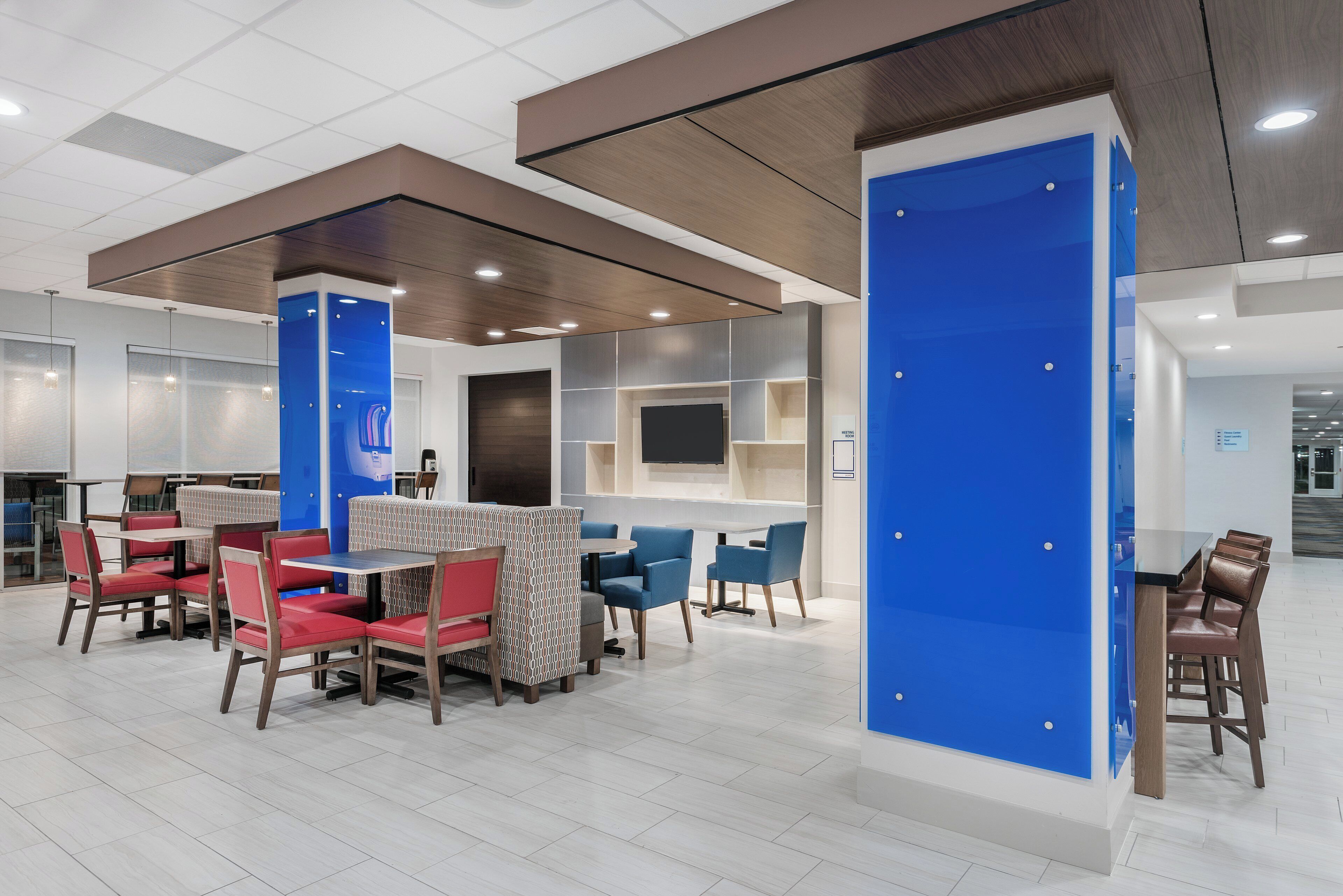 A modern interior with a central seating area, a large blue accent wall, and a flat-screen TV mounted on the wall.