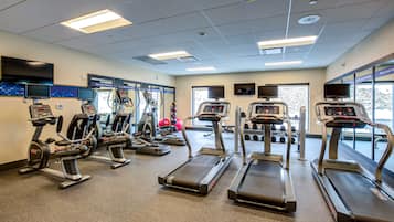 Un gimnasio con cintas de correr, elípticas y bicicletas estáticas.