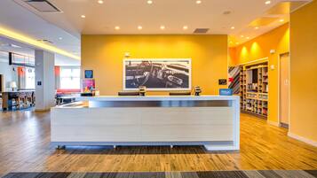 A hotel reception area with a modern design, featuring a reception desk, a large framed photograph on the wall, and a visible suite shop sign.