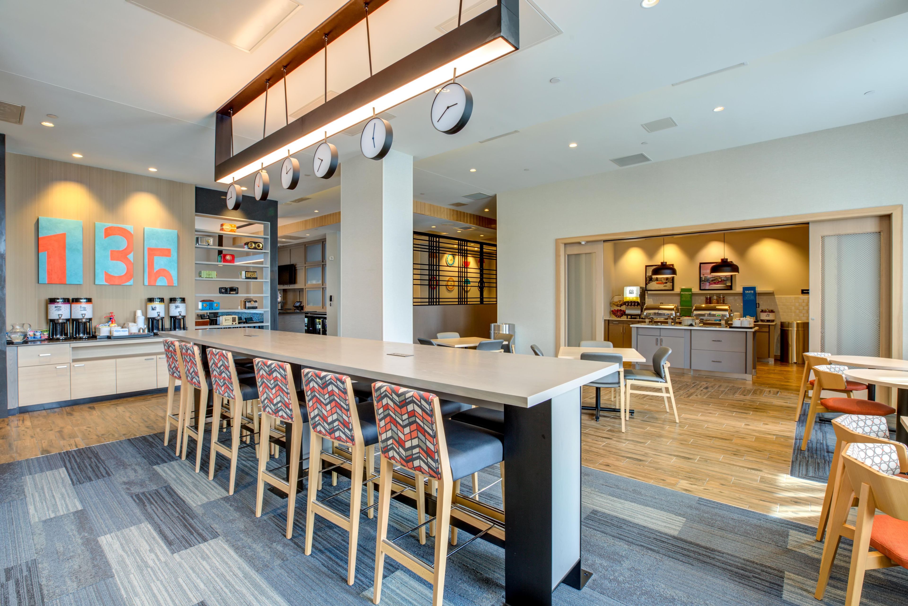 Una cocina moderna con una isla central, taburetes de bar y un comedor con una mesa grande.