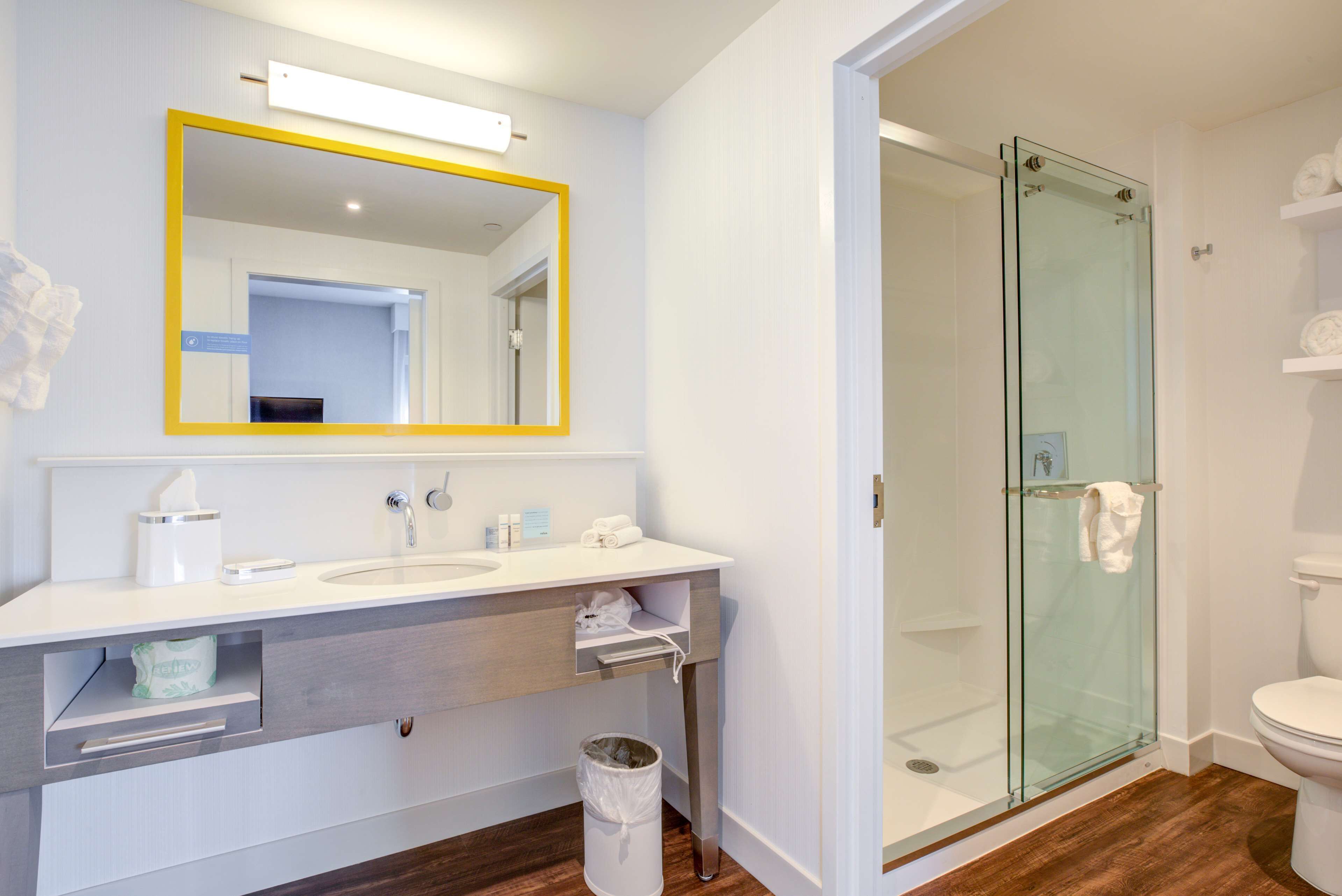 A modern bathroom with a white sink, mirror, and glass shower enclosure.
