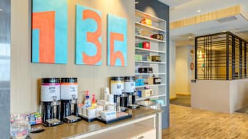 En modern hotellobby med en kaffestation, en receptionsdisk och en vägg med stora siffror.