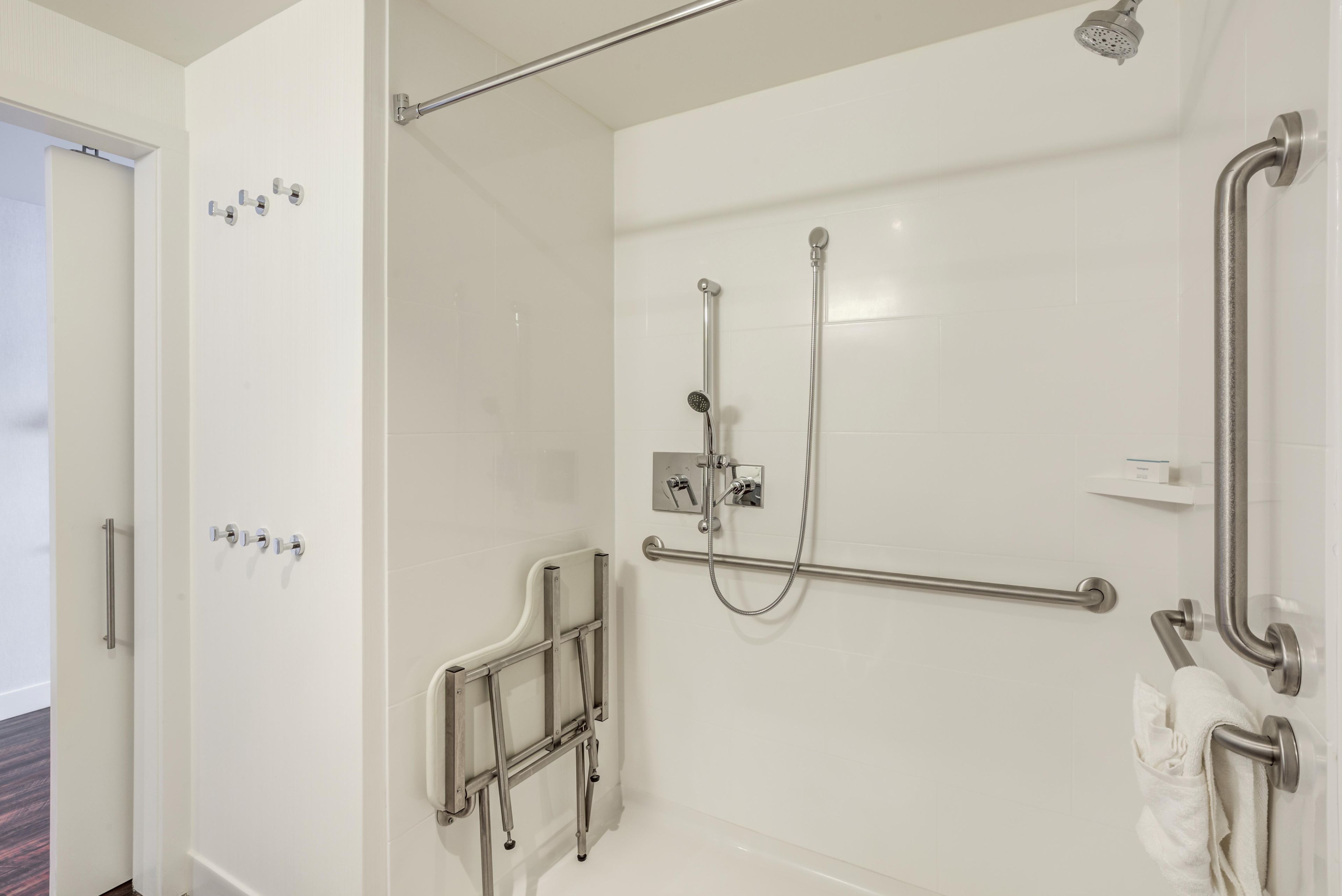 Een moderne badkamer met een inloopdouche, handgrepen en een handdoekrek.