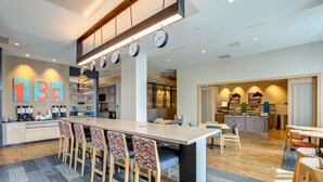 Une cuisine moderne dotée d’un îlot central, de tabourets de bar et d’un coin repas avec une longue table.