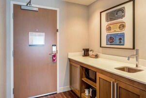 Una cocina moderna con encimera blanca, pileta de acero inoxidable y armarios de madera.