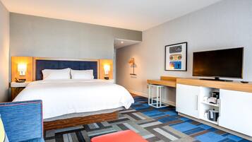 Ein Hotelzimmer mit Bett, Nachttischen, Fernseher, Schreibtisch und Stuhl.