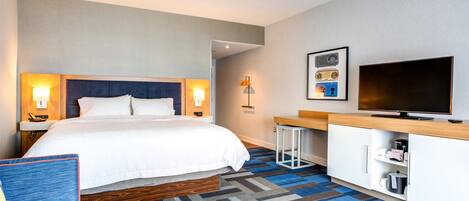 Ein Hotelzimmer mit Bett, Nachttischen, Fernseher, Schreibtisch und Stuhl.