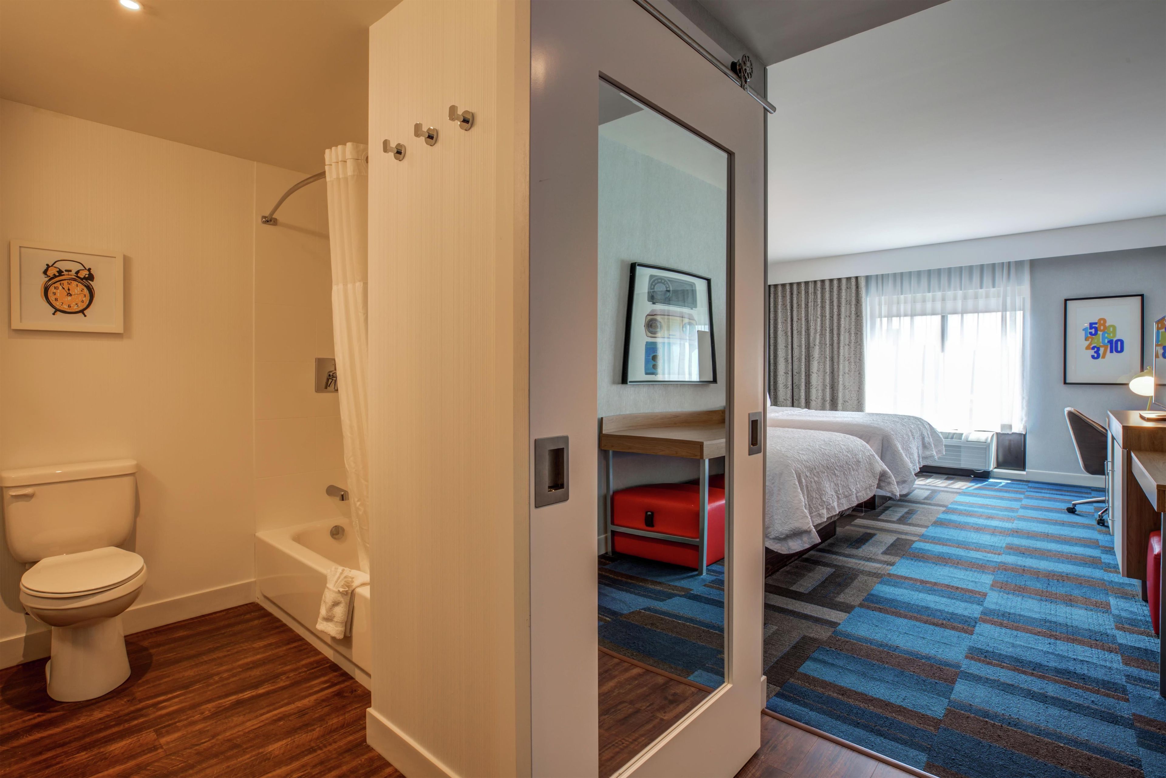 Une chambre d’hôtel équipée d’une douche, de toilettes, d’un lit, d’une table de chevet et d’un miroir.