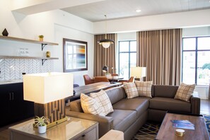 A modern living room with a sofa, coffee table, and a dining area with a table and chairs. - Hotel Indigo Hattiesburg by IHG (Hattiesburg)