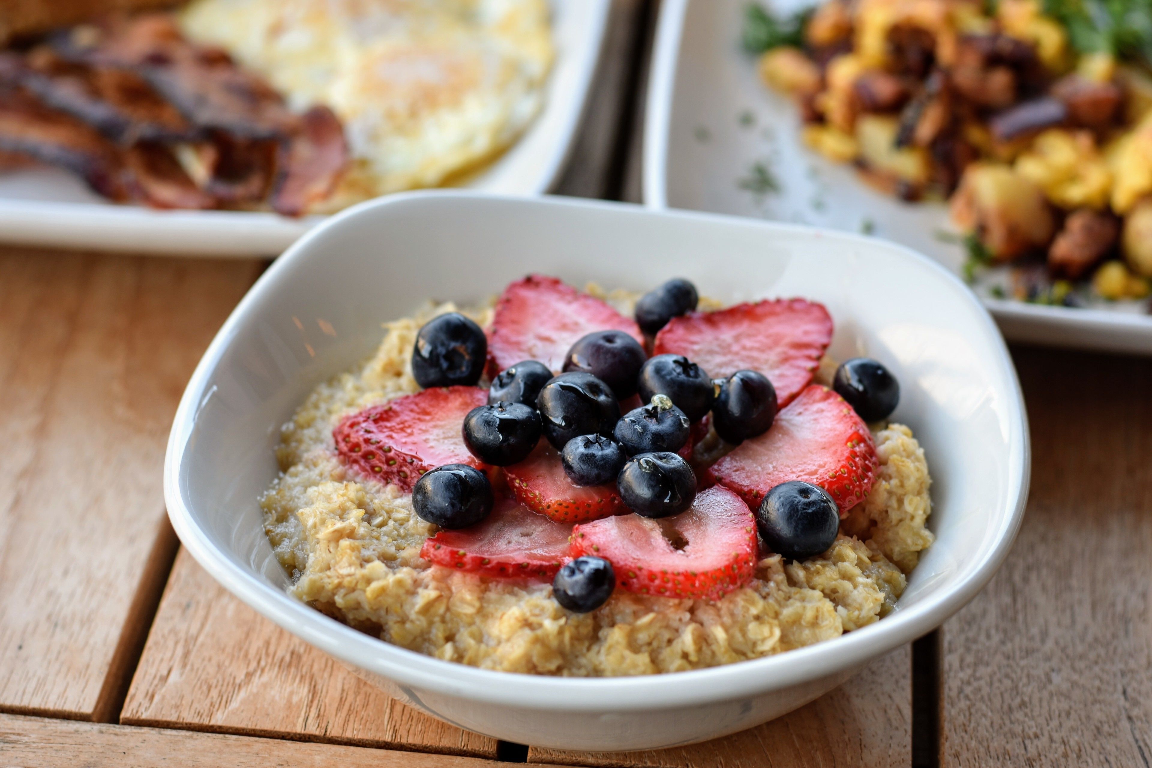 A bowl of oatmeal topped with strawberries and blueberries.