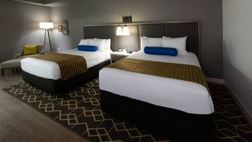 A hotel room with two beds, a nightstand, a lamp, and a patterned rug.