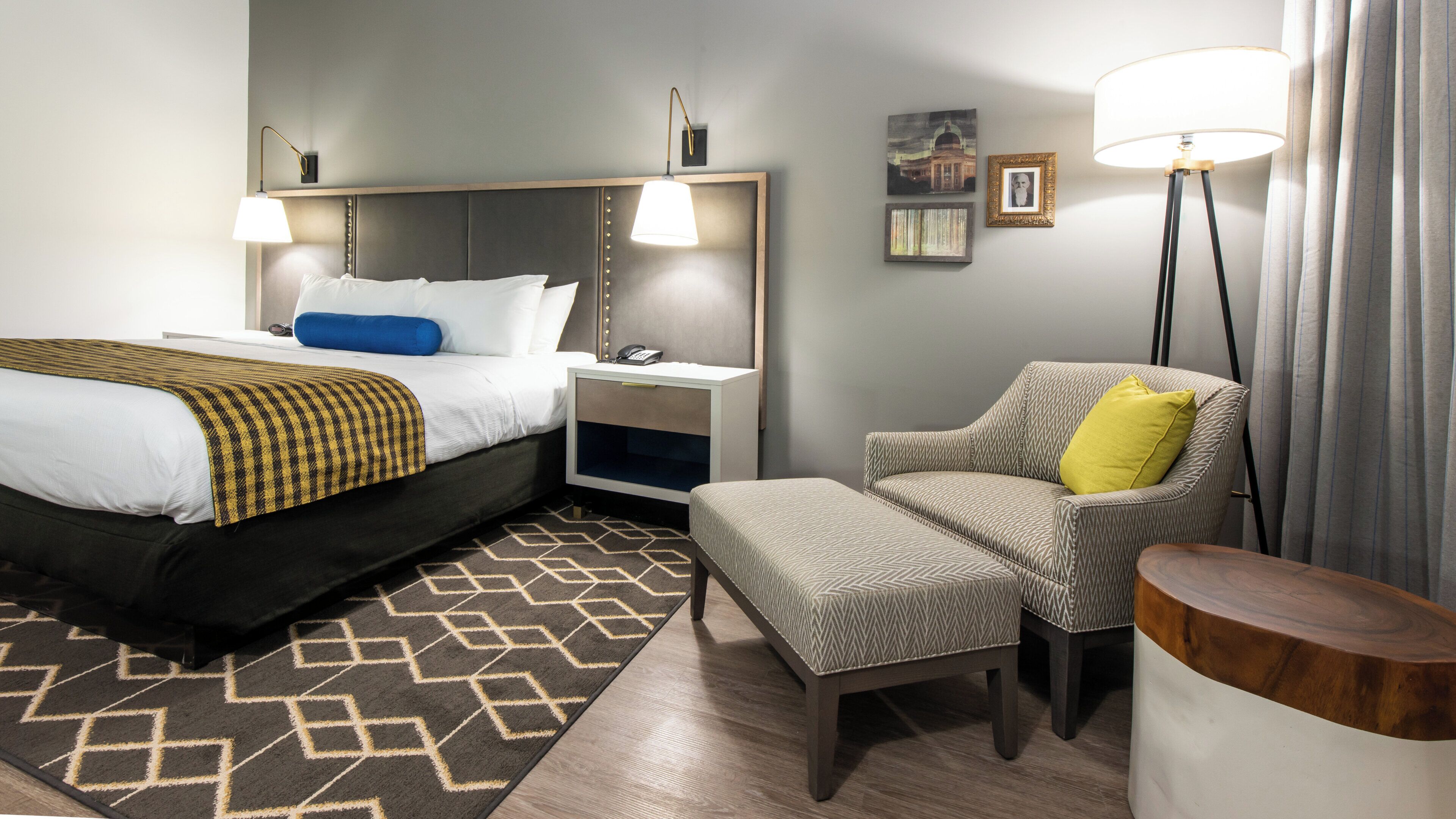 Een hotelkamer met een bed, nachtkastje, stoel en lamp.