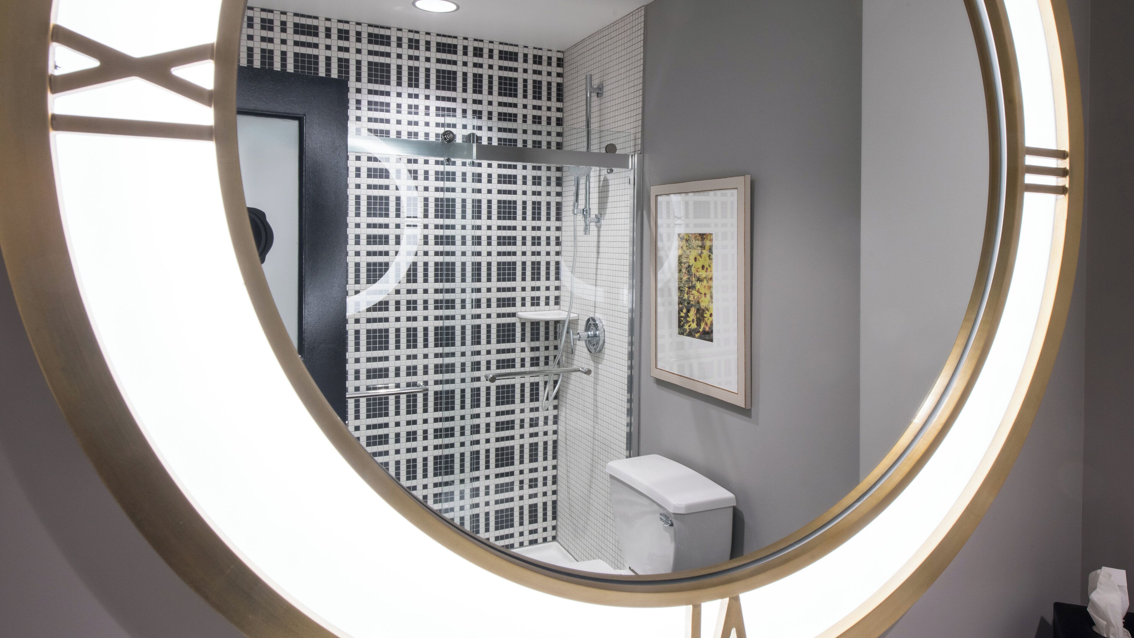 A bathroom with a checkered tile wall, a framed picture, and a toilet.