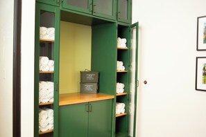 A green storage cabinet with shelves containing rolled towels and a box labeled '100 CRTR 50 CAL'. - Hotel Indigo Hattiesburg by IHG (Hattiesburg)
