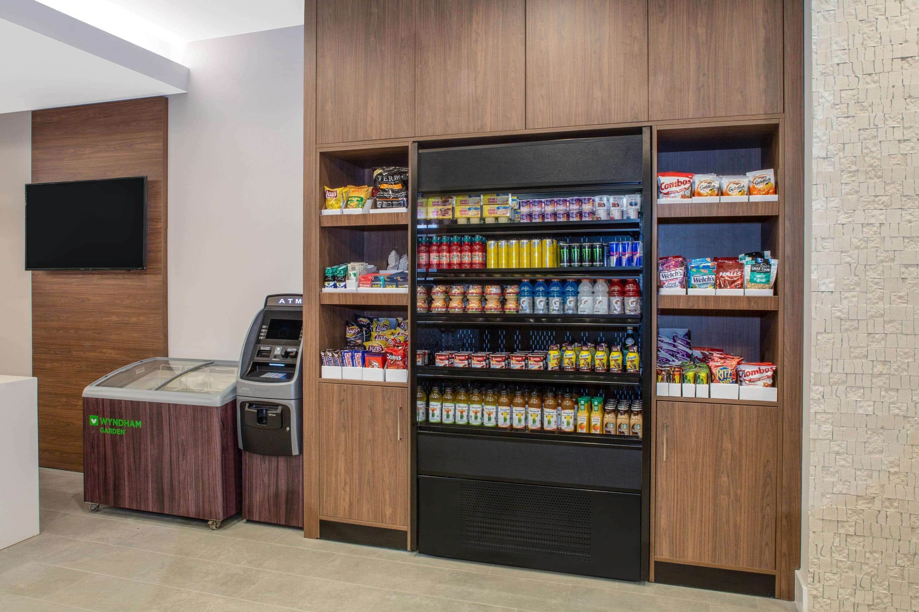 Una estación de bebidas autoservicio con diversas opciones de bebidas, aperitivos y un sistema de pago sin efectivo.