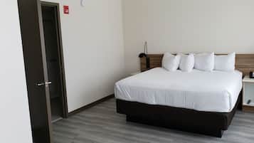 Une chambre d’hôtel comprenant un lit, des tables de chevet, une commode, une lampe et un détecteur d’incendie.