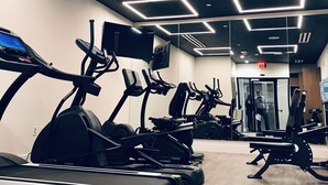 Een fitnessruimte met loopbanden, hometrainers en krachttrainingsapparatuur.