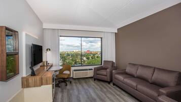 A modern living room with a large window, a flat-screen TV, a sofa, a coffee table, and a chair.