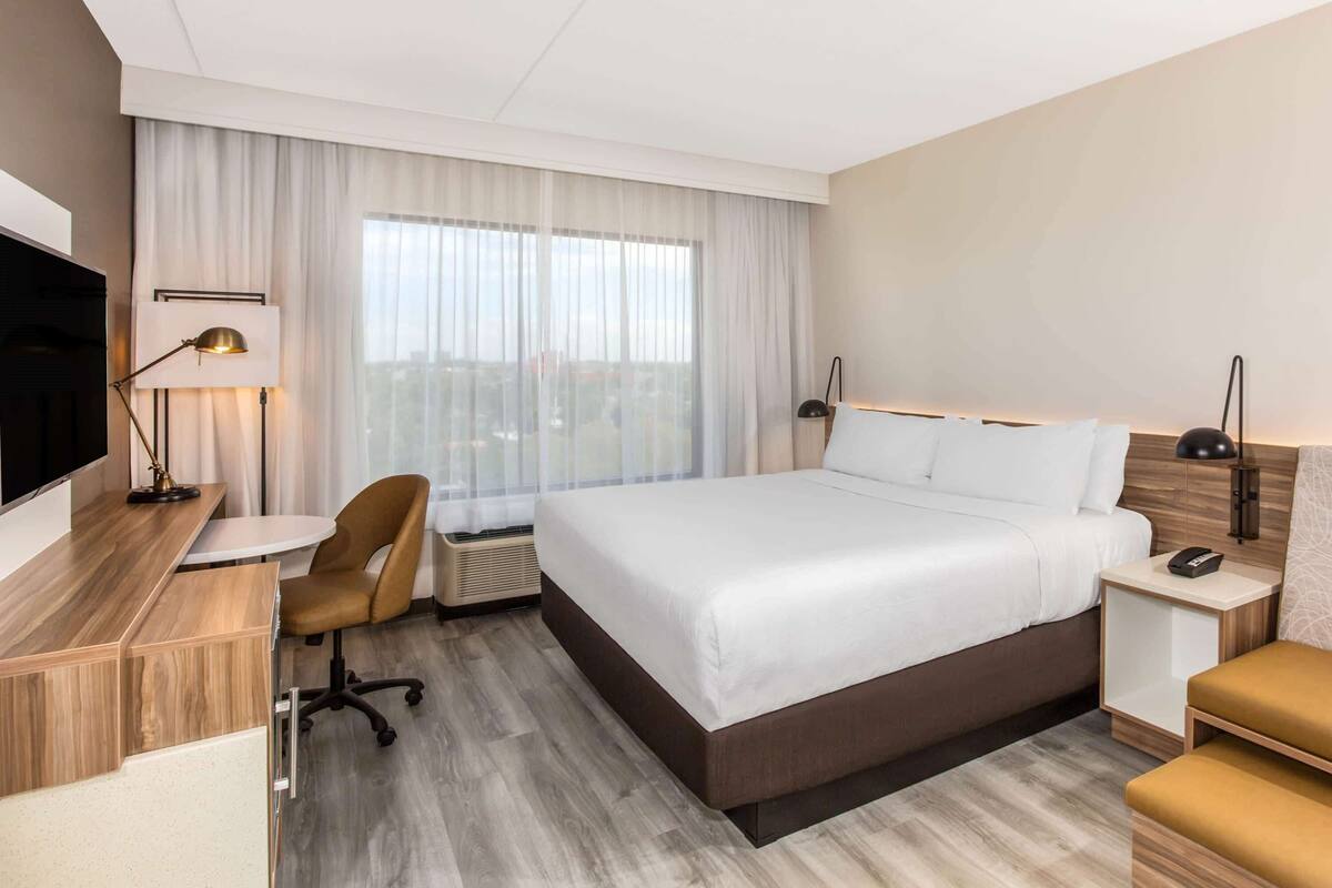 Habitación de hotel con cama, escritorio, silla y televisor.