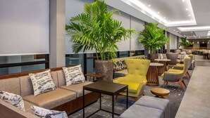 Un vestíbulo moderno con un sofá, sillones, una mesa de centro y plantas en macetas.