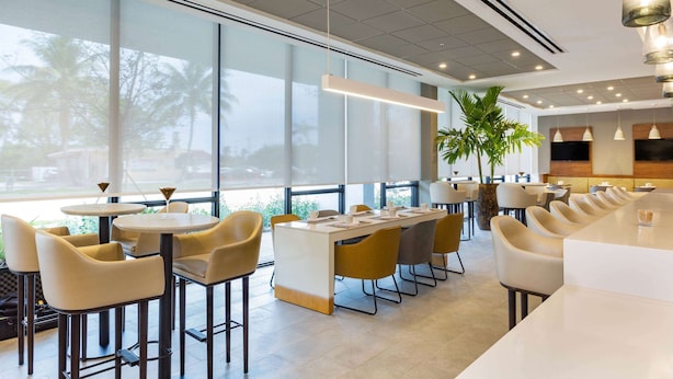 Un restaurante moderno con una larga mesa compartida, mesas individuales y sillas.