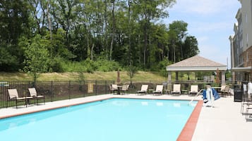 A swimming pool with lounge chairs and a gazebo.
