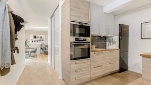 Een moderne keuken met een ingebouwde oven, een koelkast en houten kastjes.