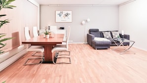 Een moderne woonkamer met een houten eettafel, een grijze bank en een wereldkaart in een lijst aan de muur.