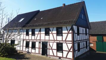 Traditional house with a steeply pitched roof and central entrance, set amidst a well-maintained property.