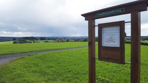 A wooden signpost with a green sign reading "Familienwanderweg" and a white informational board with a drawing and text. - Gräfrath Gästehaus Neunkirchen-Seelscheid (Neunkirchen-Seelscheid)