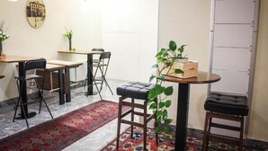 Een kamer met een eettafel, stoelen, een klein rond tafeltje met een plant en een bank.