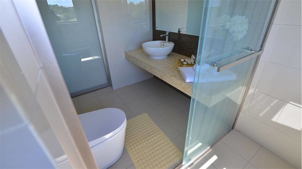 Ein modernes Badezimmer mit Duschkabine aus Glas, einem weißen Waschbecken und einer Toilette.