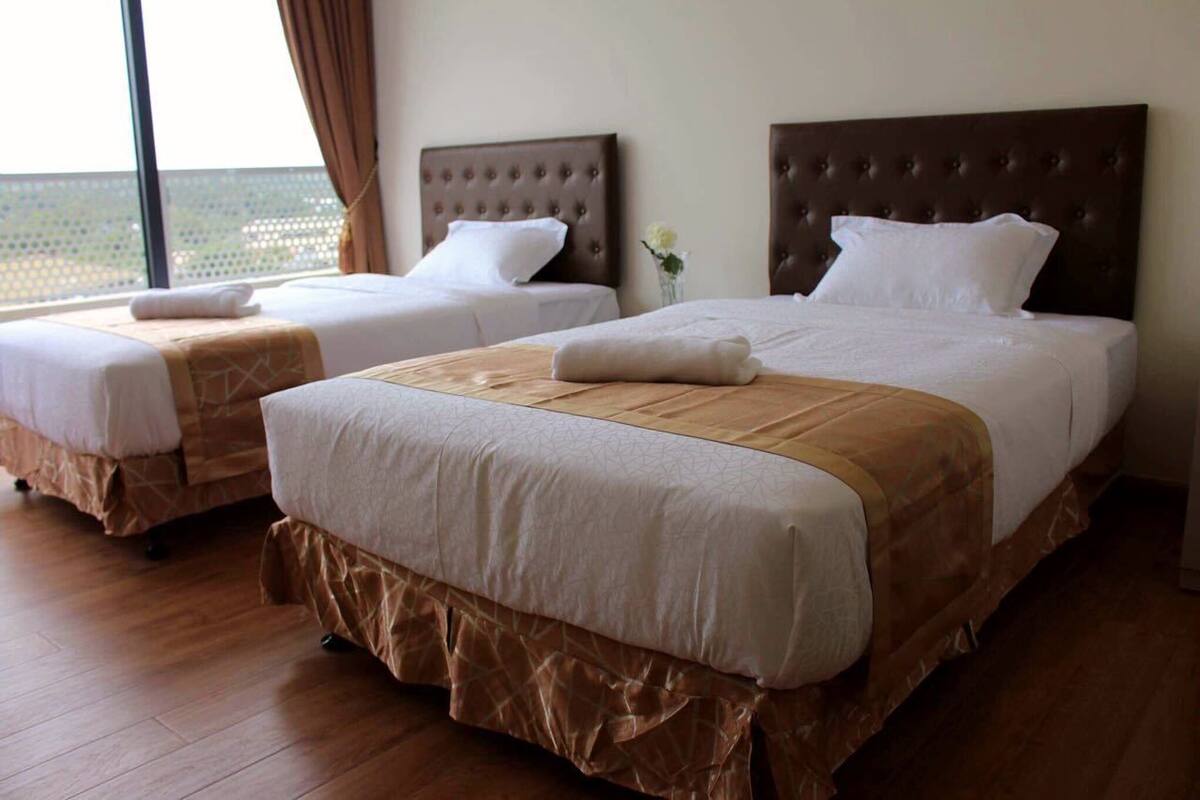 A hotel room with two beds, each with a brown headboard and white bedding.