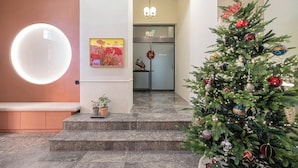 En moderne hotellobby med et juletræ, en rund lampe og en dør til et værelse.