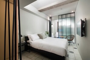 A modern bedroom with a bed, bedside table, chair, and a large window.
