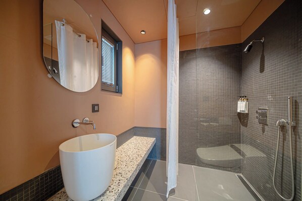 Un baño moderno con una bañera independiente grande, ducha a ras de suelo y un espejo con una toalla colgada.