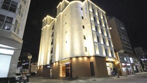 Et hotel med flere etager, en markant hjørneindgang, oplyst skiltning og en tydelig indgang i stueetagen.