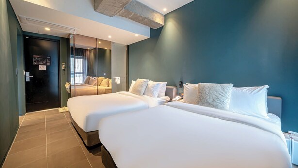 Et hotelværelse med to senge, en mørkeblå væg og et moderne design.