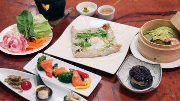 A variety of dishes on a table, including sushi, vegetables, and a bowl of soup.