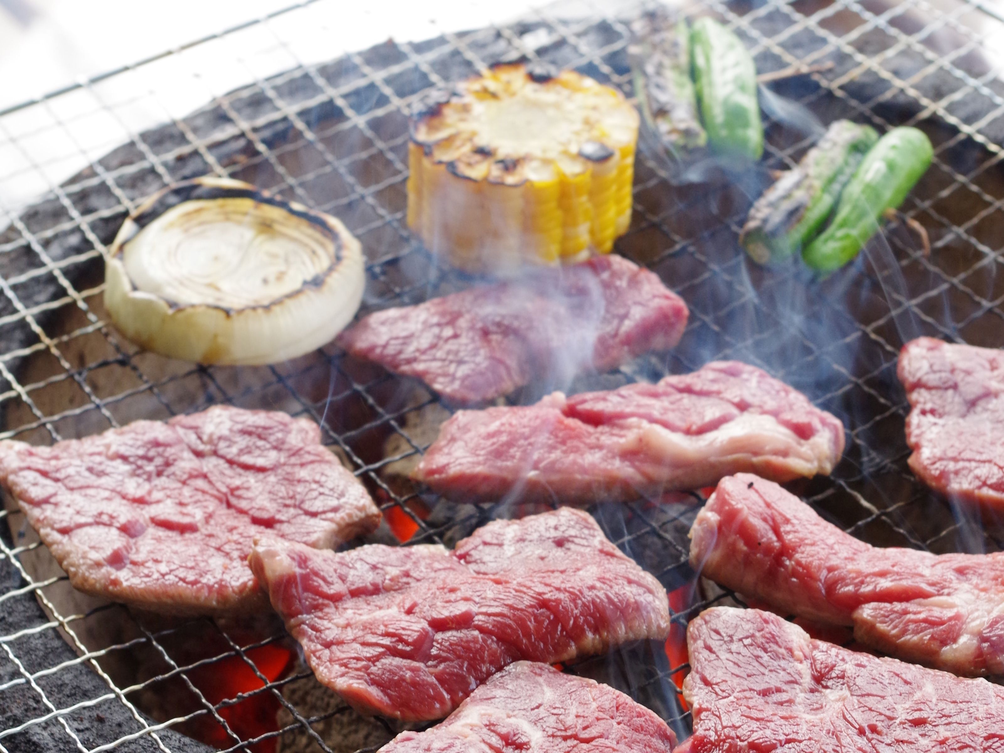 A grill with various meats and vegetables being cooked.