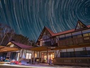 Un edificio de madera tradicional con un balcón, bajo un cielo estrellado.
